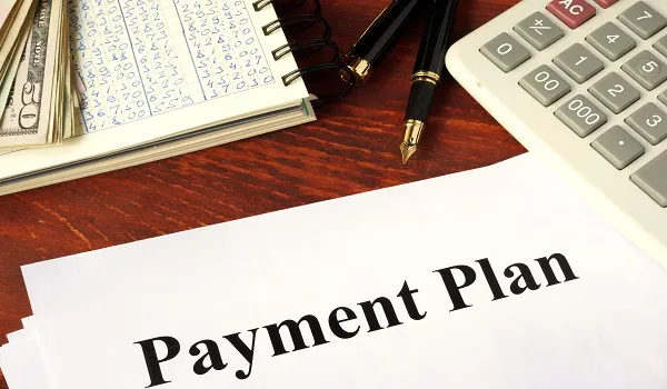Payment plan document beside a calculator and pen