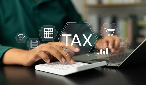 Person using a calculator beside a laptop showing tax icons
